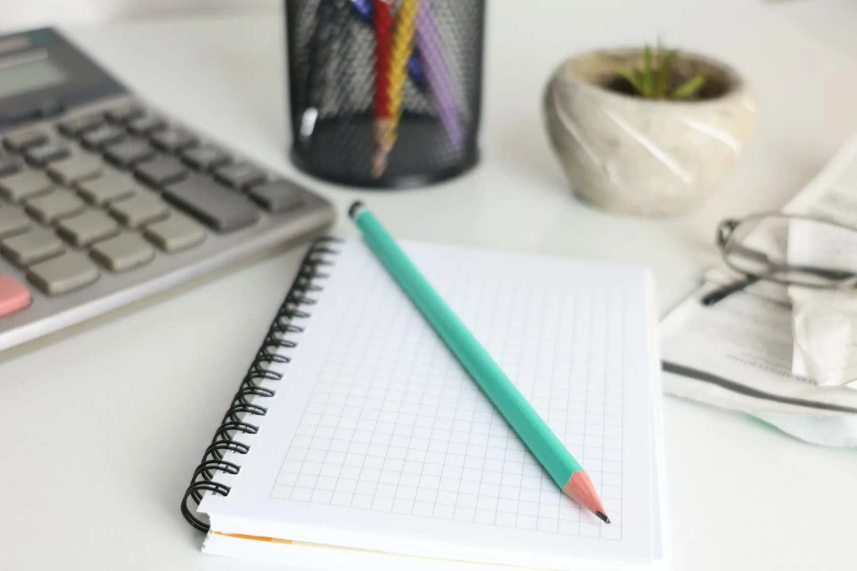 Escritorio luminoso con calculadora, cuaderno y lápiz para revisar las cuentas