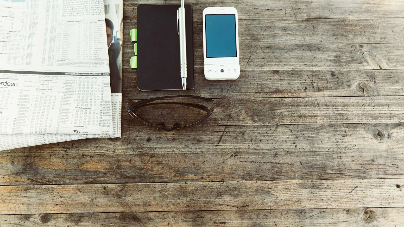 Teléfono móvil y bolígrafo sobre una mesa de madera para revisar una deuda de telefonía y su inclusión en ASNEF