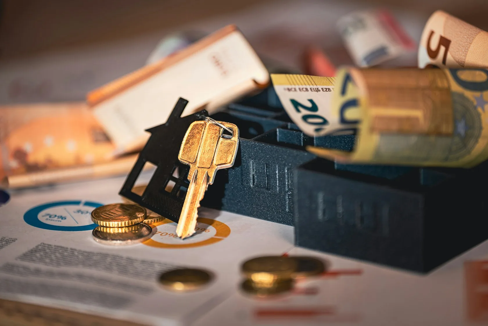 Llave con llavero de casa sobre documentos y monedas, código de buenas prácticas hipotecario para reestructurar la deuda