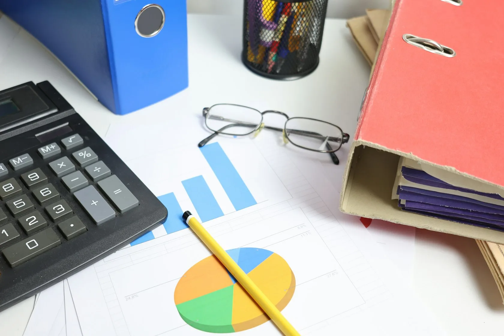 Escritorio con calculadora, gafas y gráficos para revisar deudas exoneradas en la CIRBE