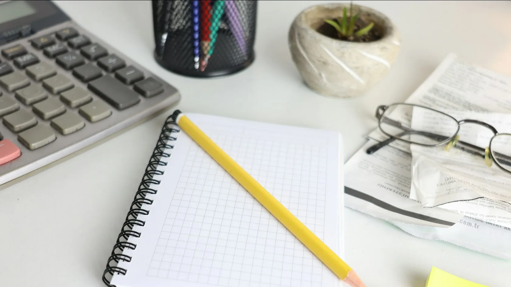 Escritorio con calculadora, cuaderno y gafas para calcular el embargo durante una baja médica