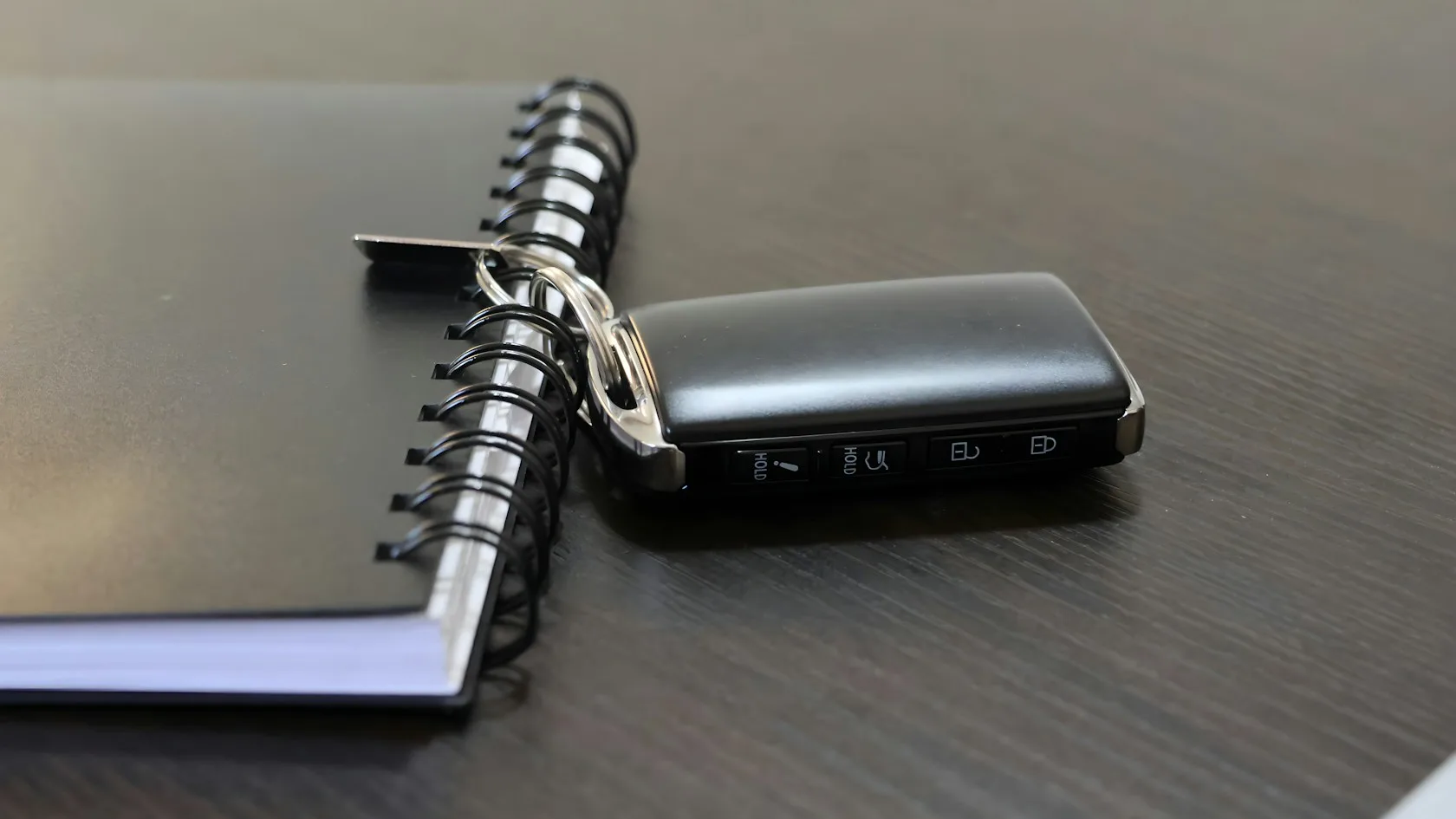 Llave de coche junto a un cuaderno sobre un escritorio para revisar un embargo de vehículo por deudas