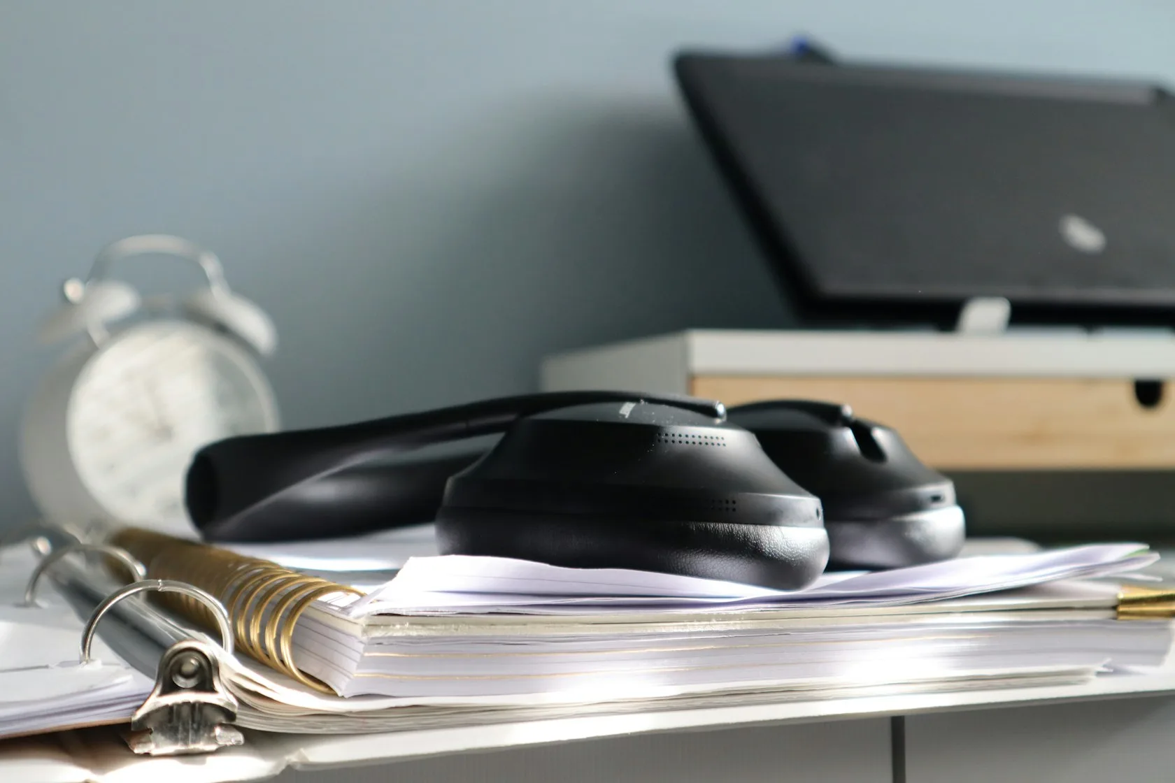 Auriculares sobre una carpeta de documentos en un escritorio: llamadas de empresas de recobro y papeleo de una deuda