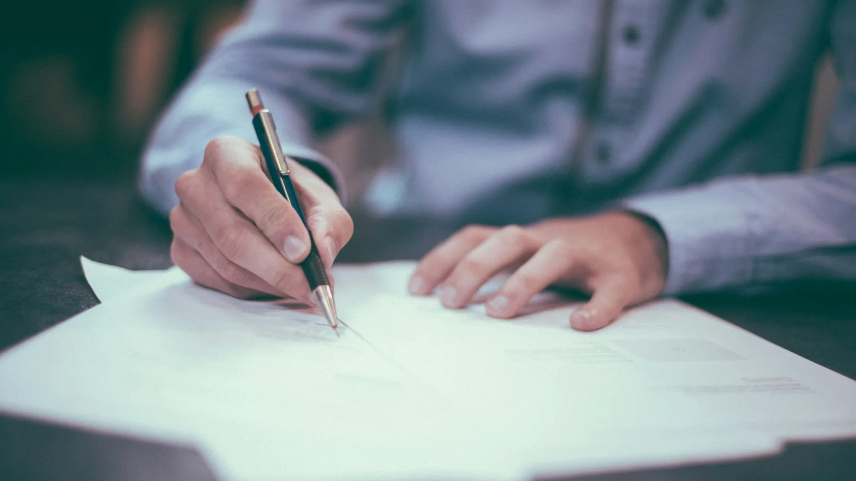 Persona firmando un documento sobre un escritorio, justificante de pago para levantar un embargo