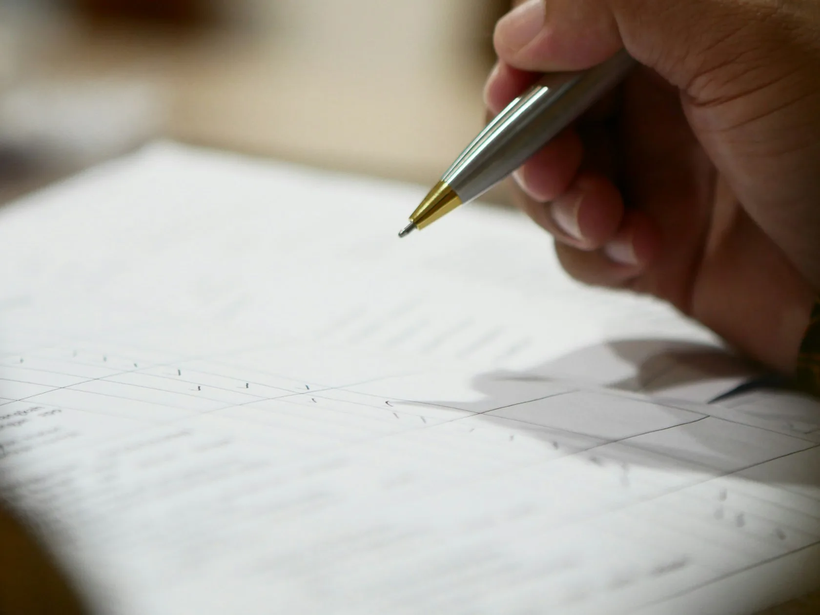 Mano con bolígrafo firmando un documento sobre la hipoteca de un familiar garante