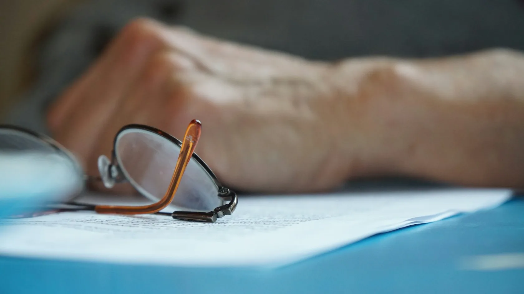 Gafas de lectura sobre un escritorio: jubilado con deudas y embargo de pensión