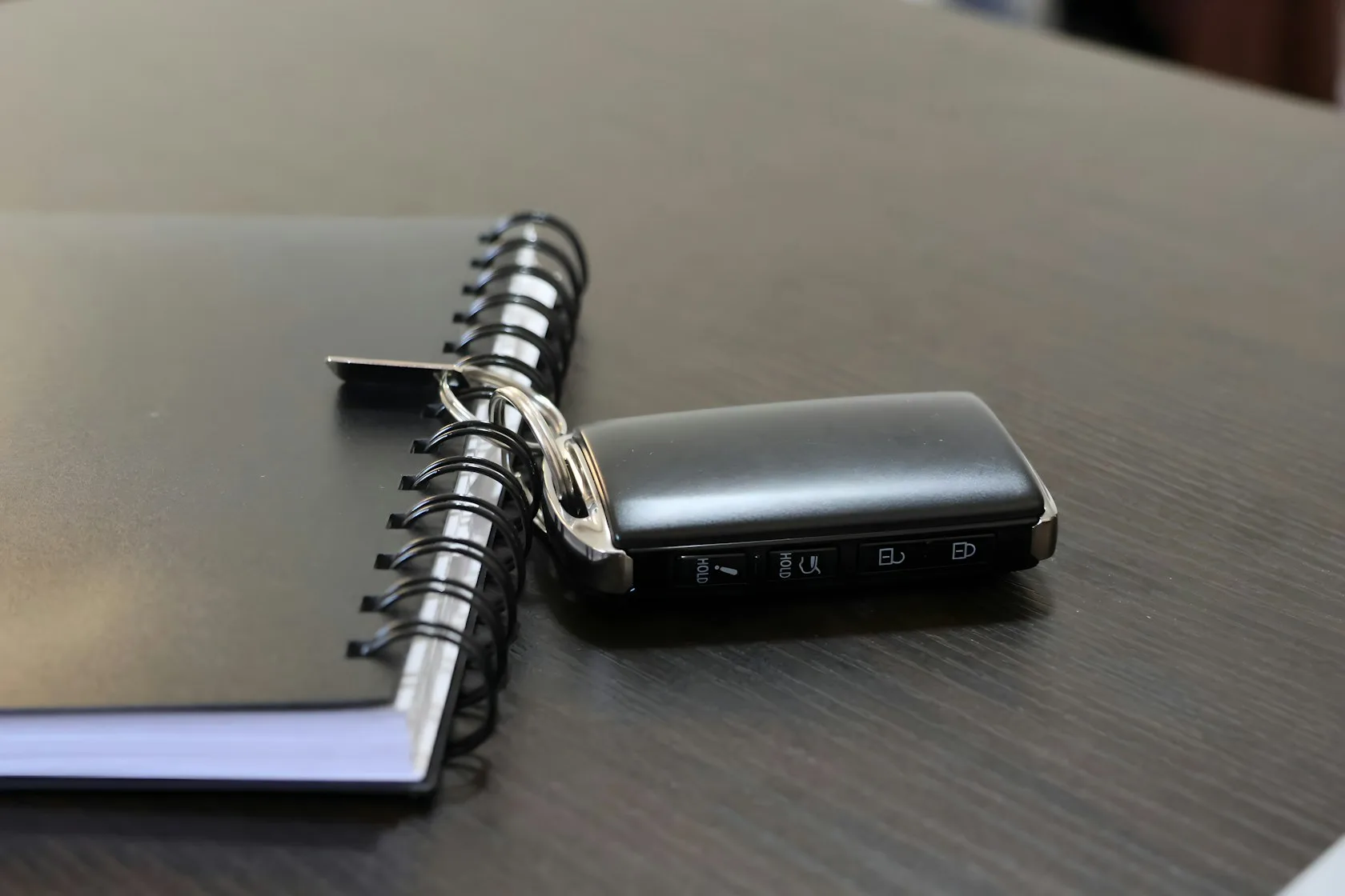 Llave de coche junto a un cuaderno sobre una mesa de oficina, vehículo financiado y deuda