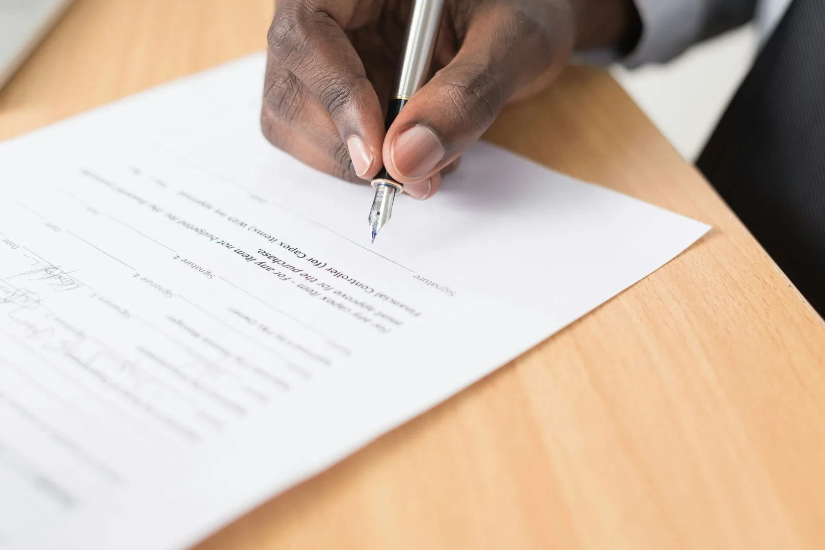 Persona firmando un escrito sobre documentos legales para responder a una invitación a negociar una deuda
