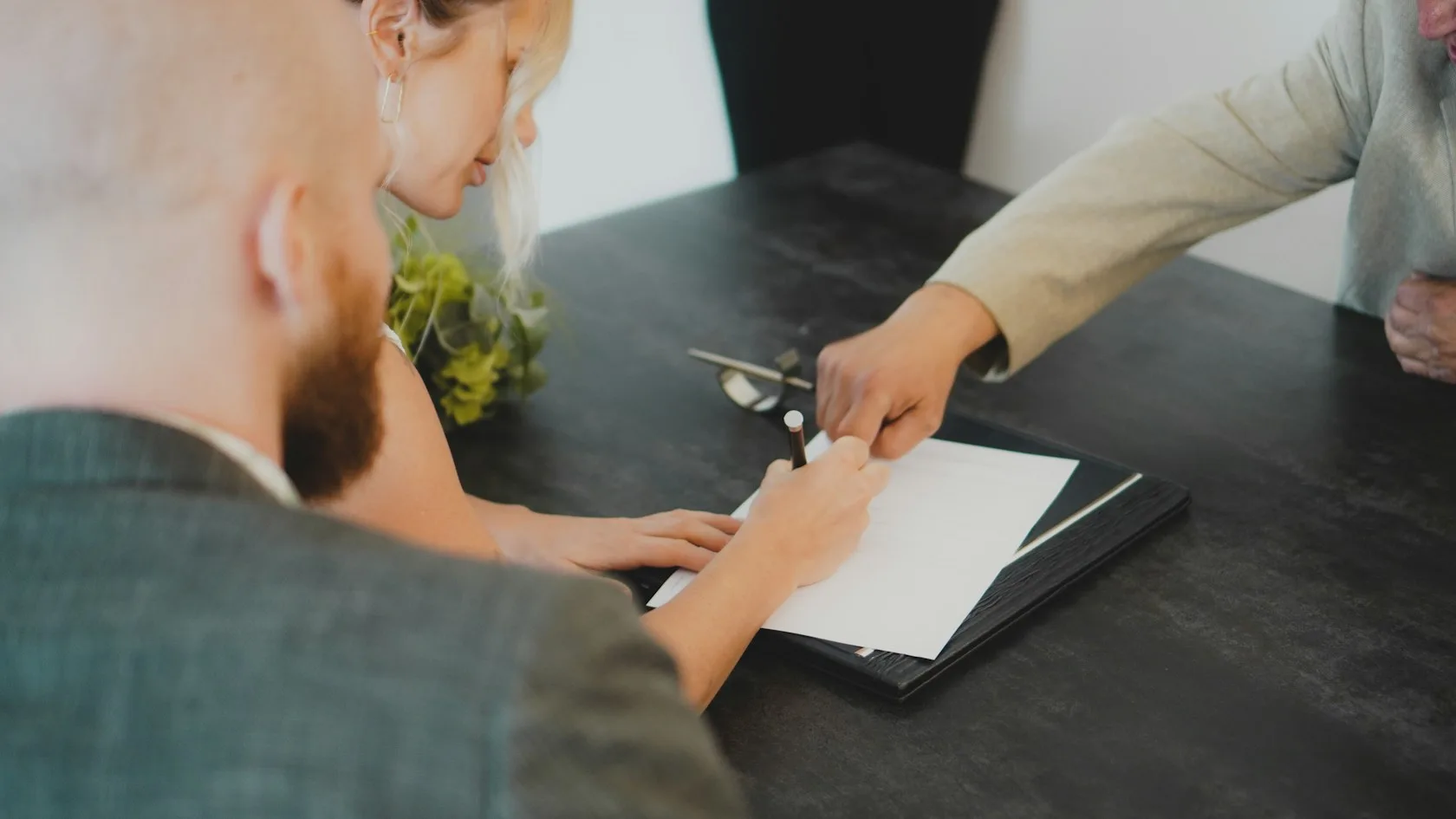 Pareja firmando un documento en un escritorio para cambiar la hipoteca variable a fija