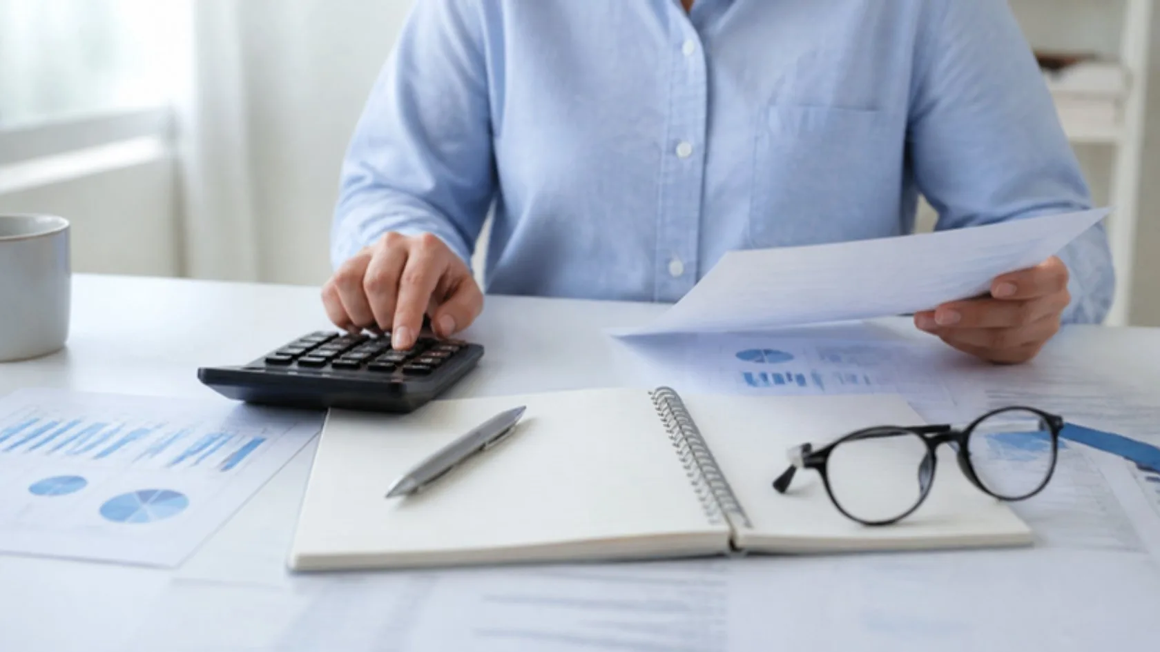 Manos con calculadora y papeles revisando el presupuesto mensual para calcular el ratio de endeudamiento