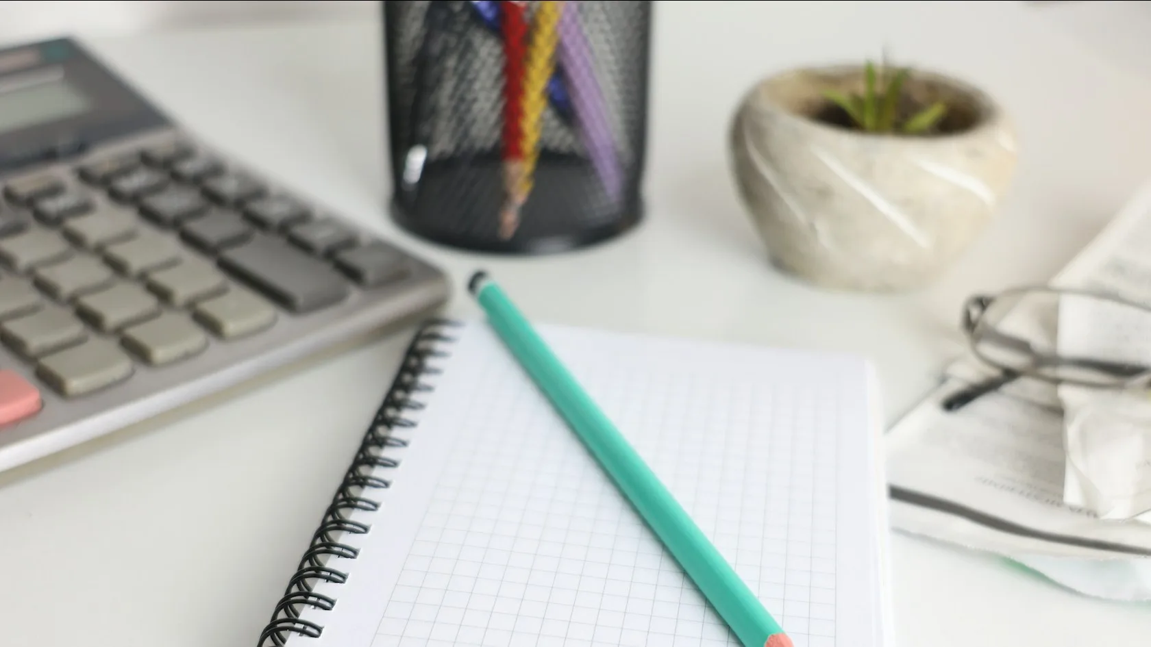 Escritorio con calculadora, cuaderno y lápiz para revisar la deuda de la tarjeta de crédito